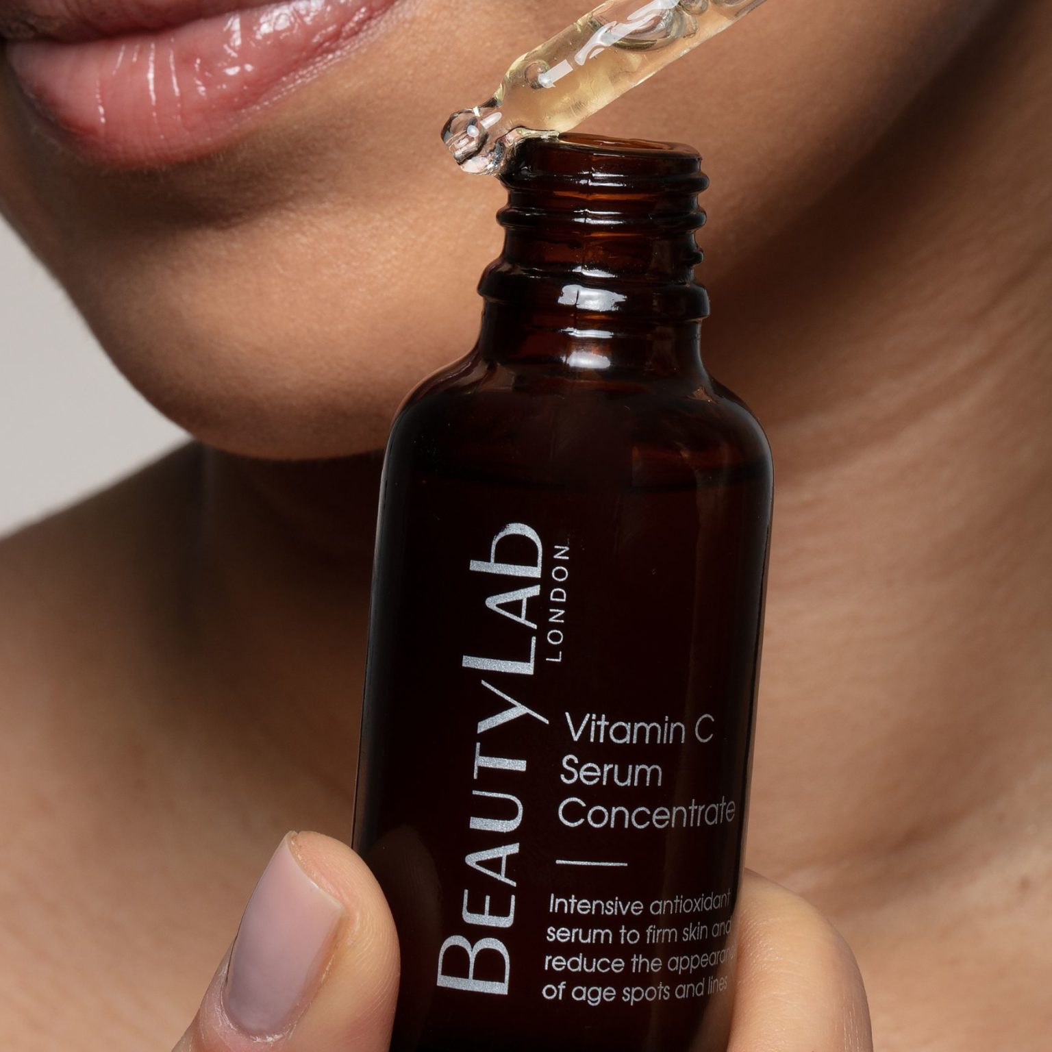 Model holding an open bottle of the Vitamin C Serum Concentrate