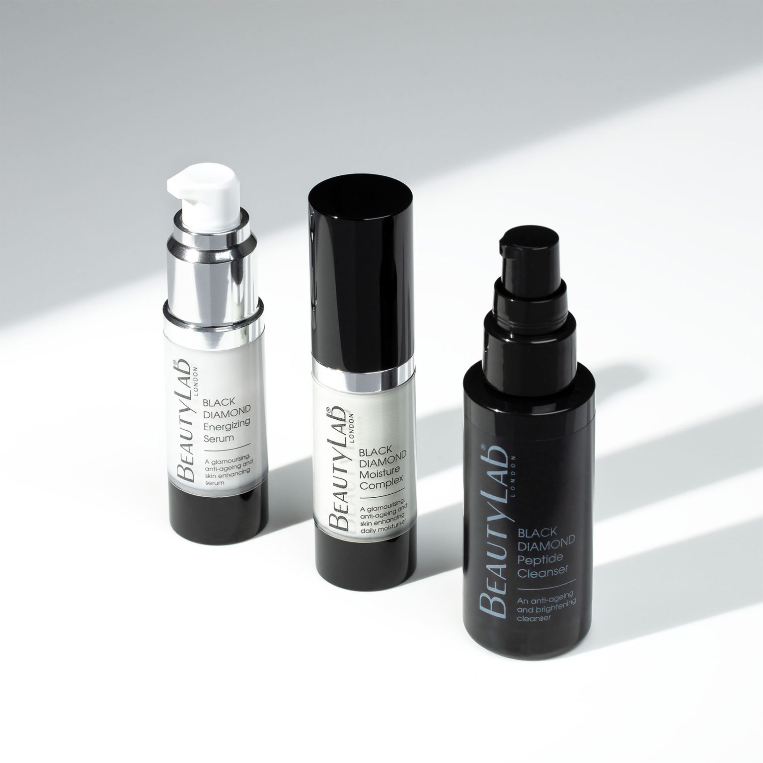 Black Diamond Energizing Serum, Black Diamond Moisture Complex and Black Diamond Peptide Cleanser against a white background