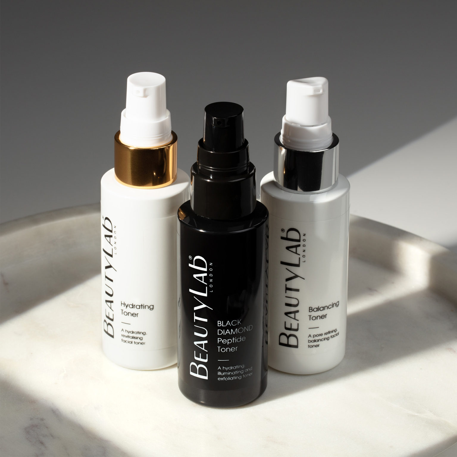 Hydrating Toner, Black Diamond Peptide Tone and Balancing Toner on top of a white marble tray