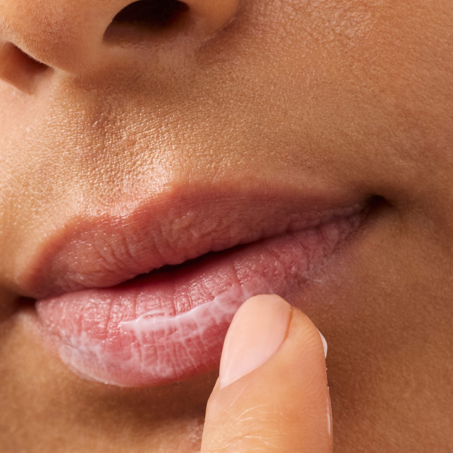 Model applying cream to her lips